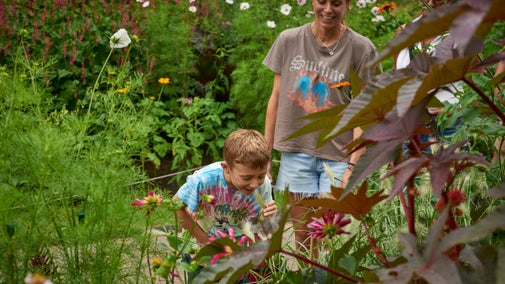 Child smelling the flowers in a tropical flower bed.